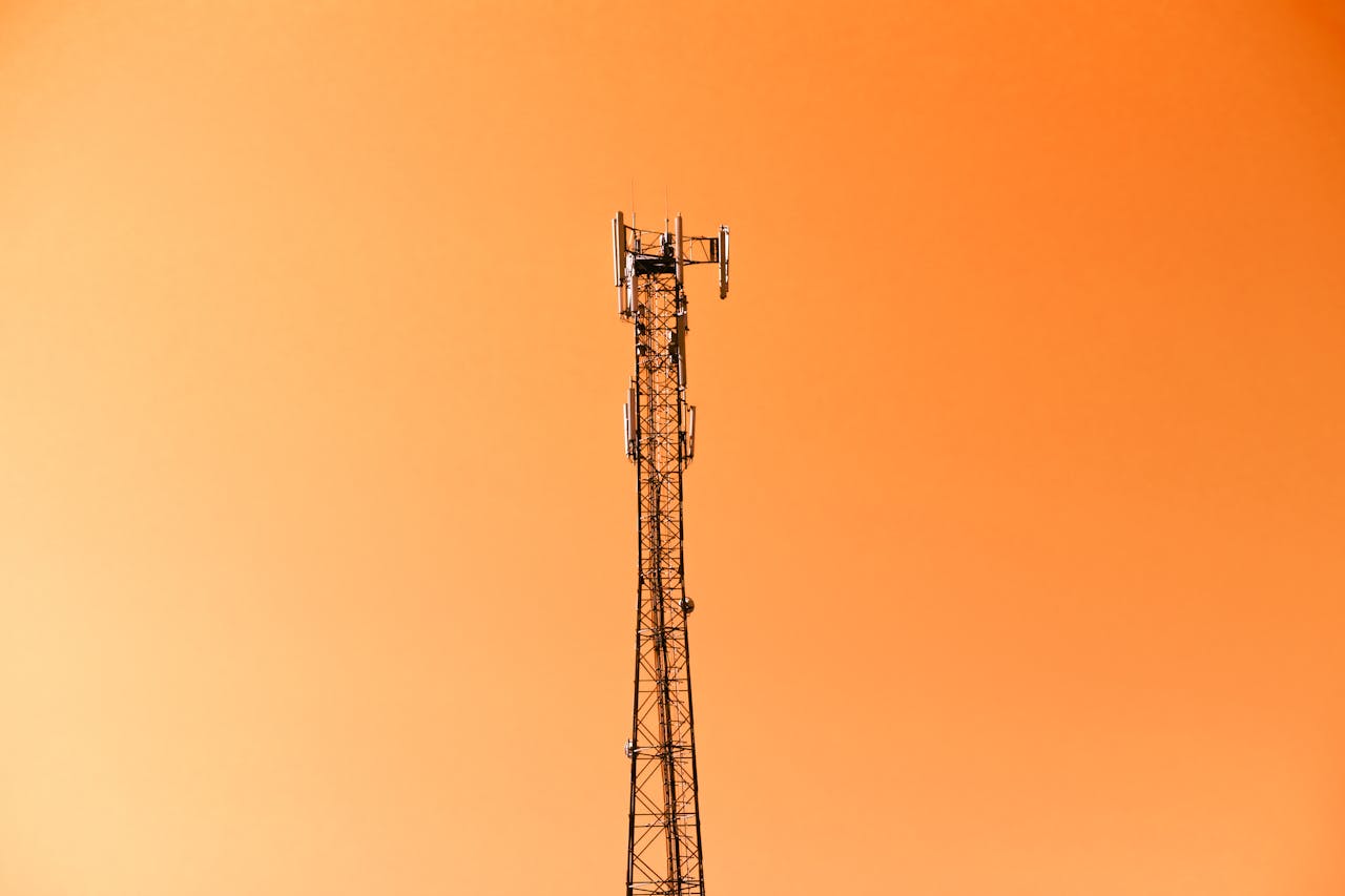 Radio mast silhouetted against a vibrant orange sky in Adana, Türkiye.